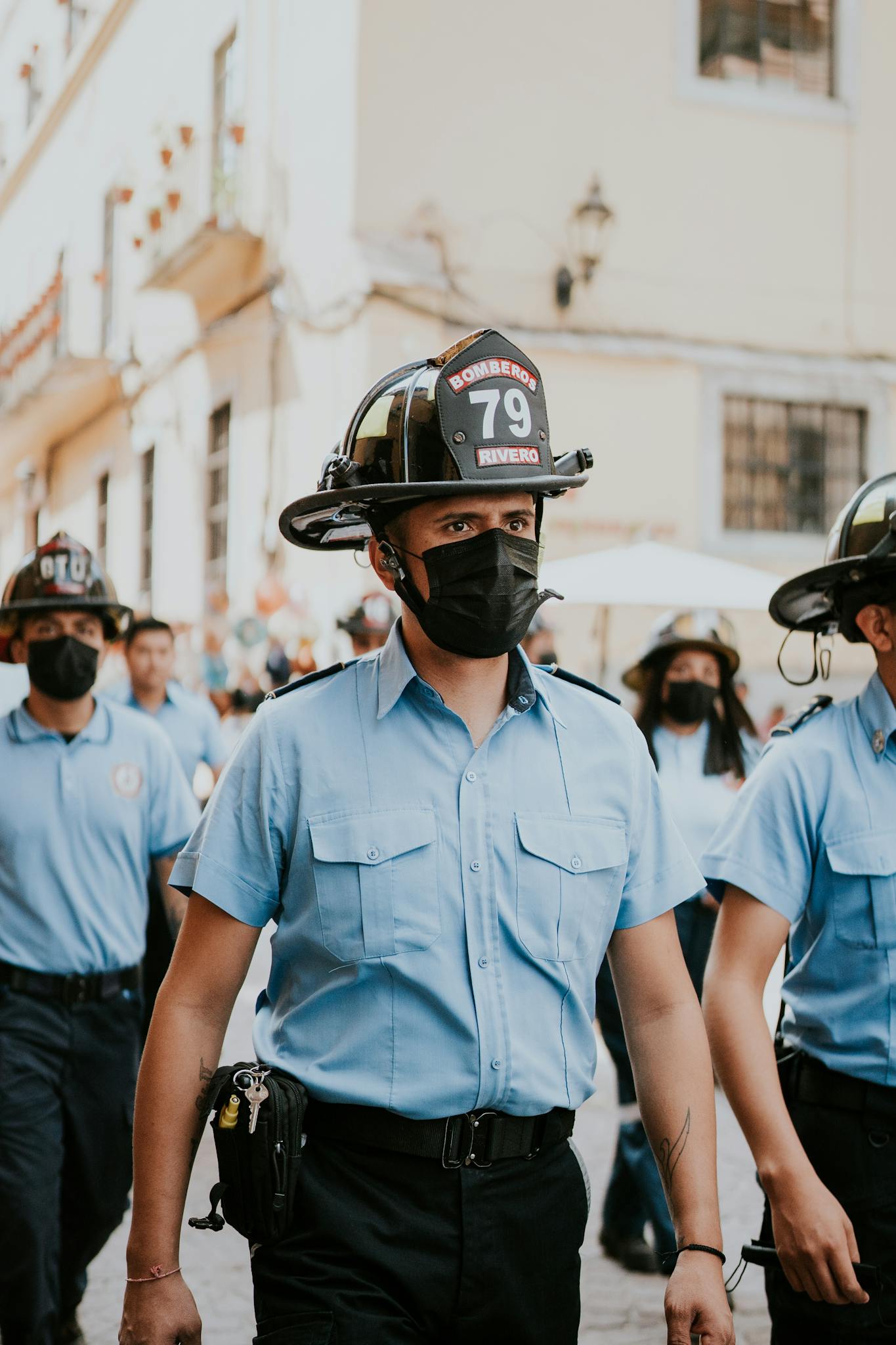 Firefighters in blue uniforms and helmets marching in an outdoor parade, showcasing teamwork and safety.